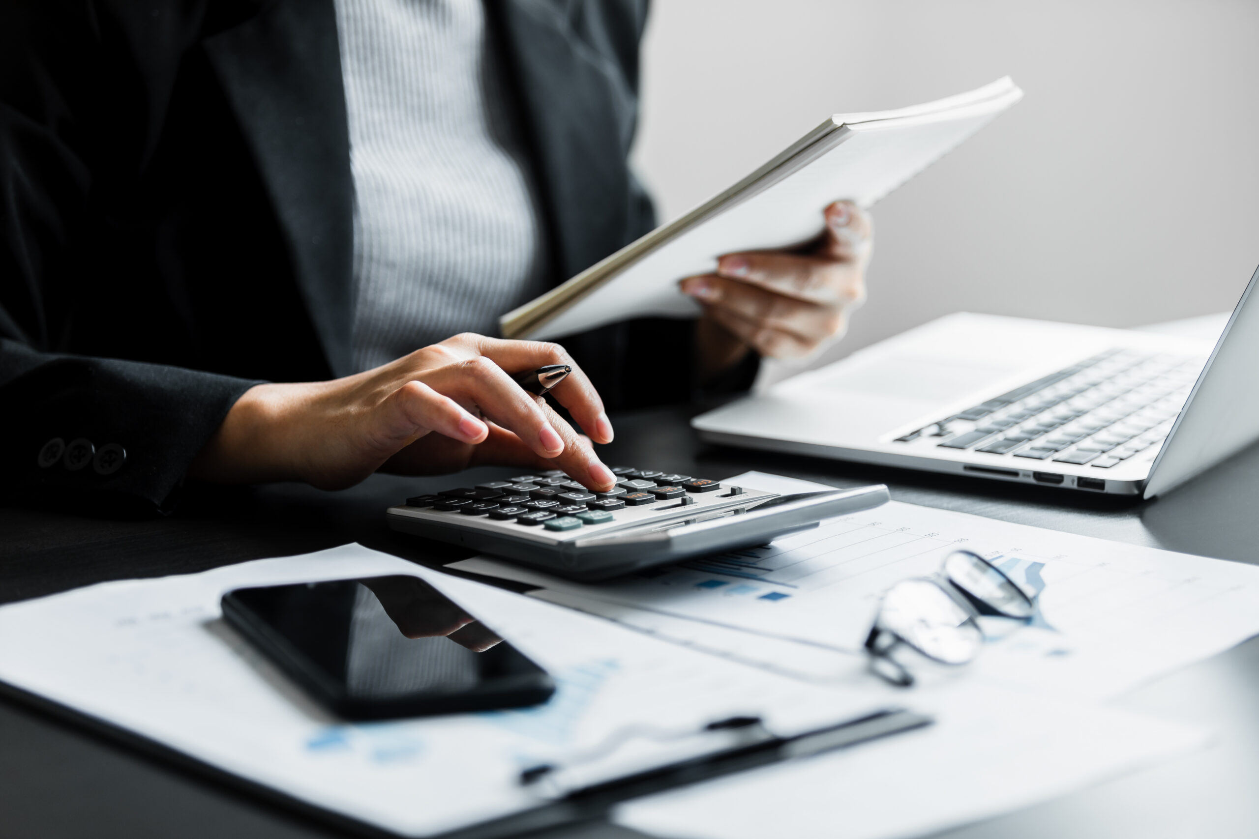 Accountant working through figures on a calculator and laptop