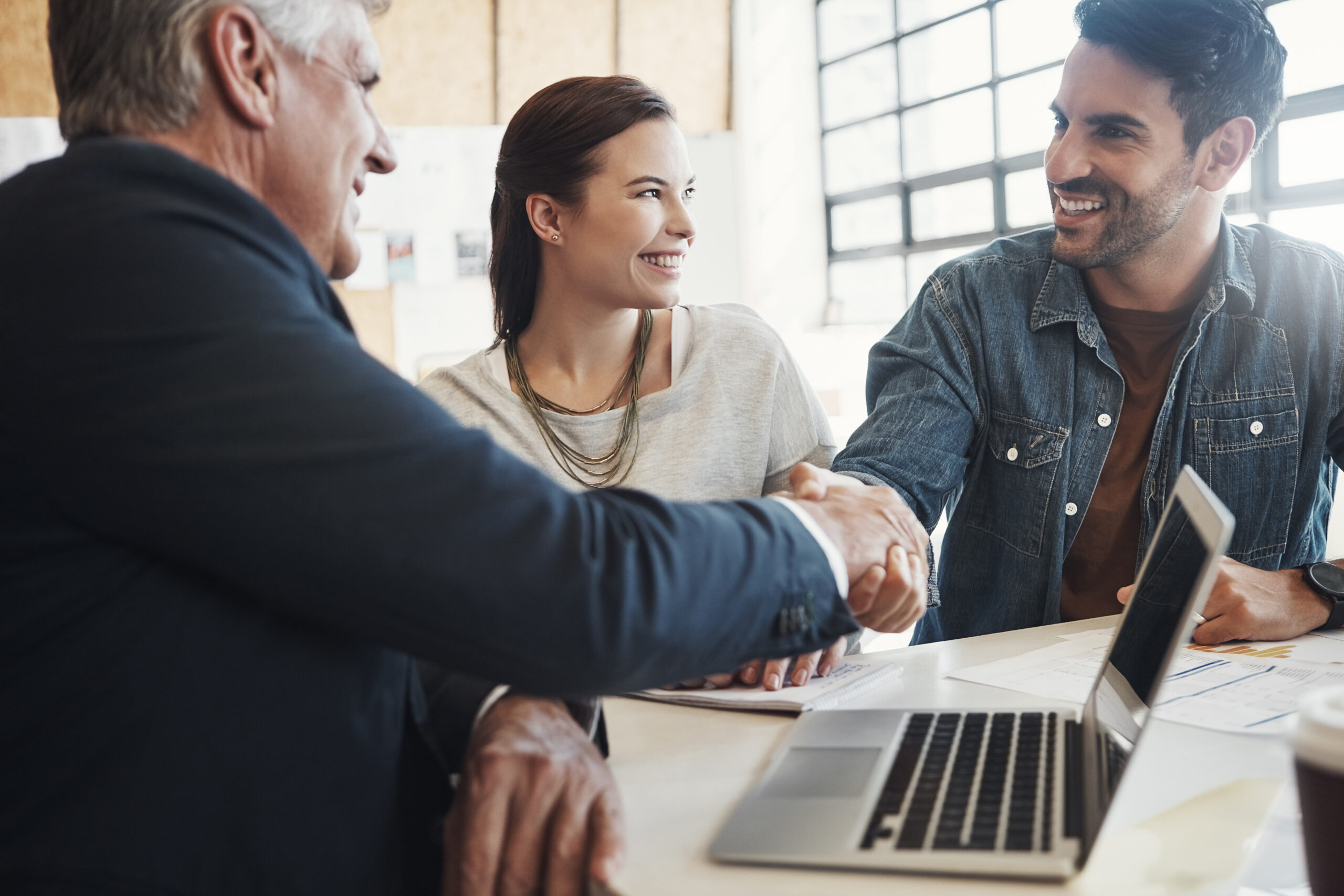 Wealth manager shaking hands with clients after a meeting